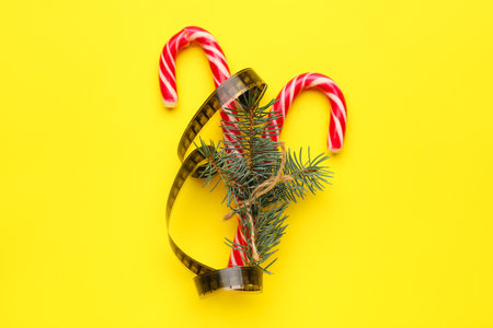 Candy canes with film reel and fir branches on yellow backgroundの写真素材