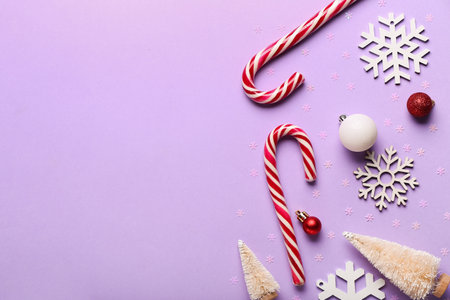 Composition with tasty candy canes, Christmas decorations and confetti on lilac backgroundの写真素材