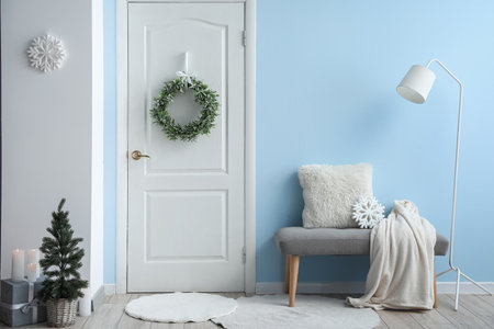Stylish Christmas mistletoe wreath hanging on door in roomの写真素材