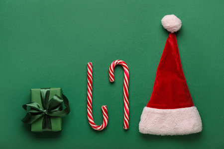 Candy canes with Christmas gift and Santa hat on green backgroundの写真素材