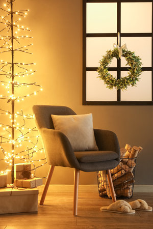 Interior of living room with Christmas mistletoe wreath, armchair and glowing lightsの写真素材