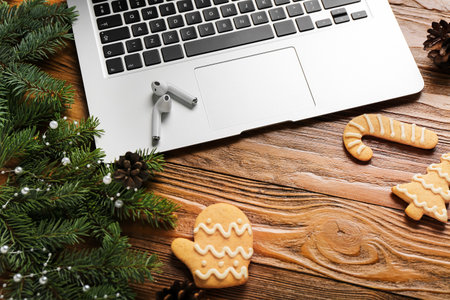 Composition with fir branches, Christmas cookies, earphones and laptop on wooden background, closeup