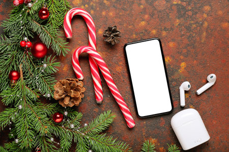 Composition with fir branches, candy canes, mobile phone and earphones on grunge backgroundの写真素材