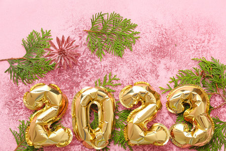 Figure 2023 made of balloons with Christmas branches and glitter on pink background