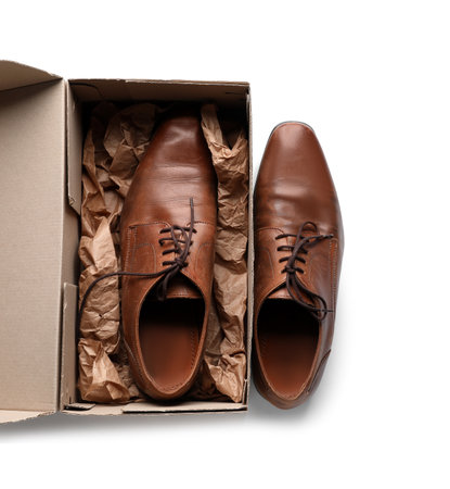 Cardboard box with brown shoes on white backgroundの写真素材