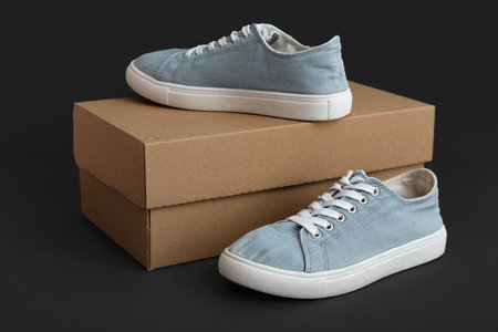 Cardboard box with blue sneakers on dark background