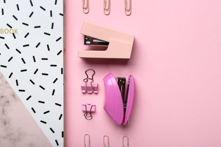 Composition with notebook, staplers and paper clips on pink background, closeupの写真素材