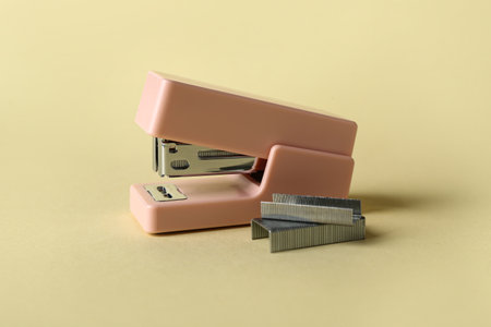 Pink office stapler and staples on color backgroundの写真素材