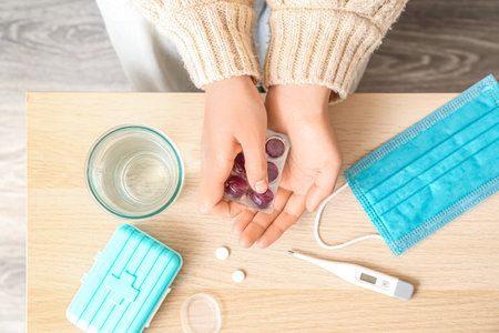 Woman taking pills for sore throat at home, closeup