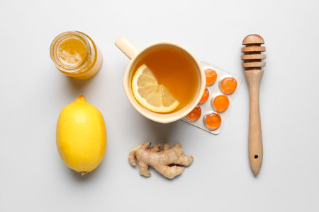 Pills for sore throat, cup of tea, lemon, ginger and honey on light backgroundの写真素材