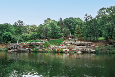 View of beautiful park with green trees, rocks and river