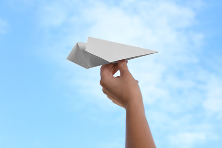 Woman with paper plane against blue sky, closeupの写真素材