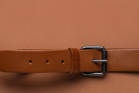 Leather belt with buckle on brown background