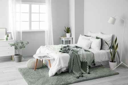 Interior of light room with big bed, houseplants and tablesの写真素材