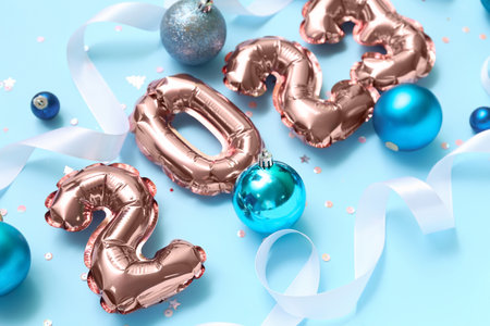 Figure 2023 made of foil balloons with Christmas balls and ribbons on blue background