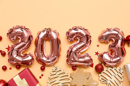 Figure 2023 made of foil balloons with Christmas decor, gift and cookies on beige background
