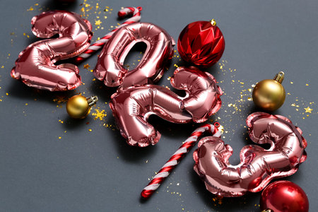 Figure 2023 made of foil balloons with Christmas decor on black background, closeup