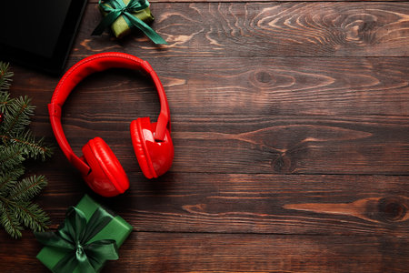 Modern headphones, Christmas gifts and fir branches on wooden backgroundの写真素材