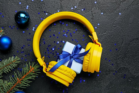 Composition with modern headphones, Christmas gift, balls and fir branch on dark backgroundの写真素材
