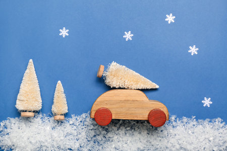 Toy car with Christmas trees, snow and snowflakes on blue backgroundの写真素材
