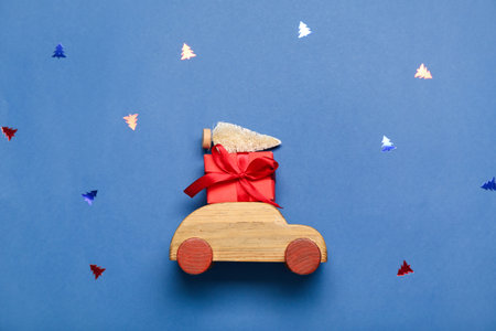 Toy car with Christmas tree and gift on blue backgroundの写真素材