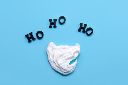 Santa beard made of cream and words HO HO HO on blue background