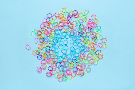Heap of colorful rubber bands on color background