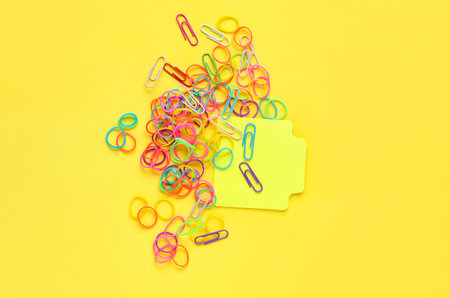 Sticky note and office rubber bands on yellow background