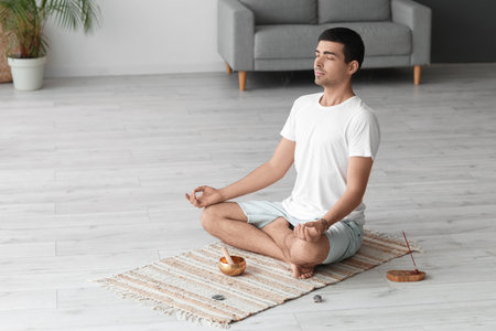 Young man with Tibetan singing bowl meditating at homeの写真素材