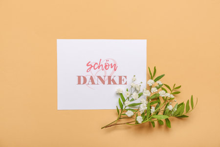 Card with text SCHON DANKE, plant branch and flowers on color backgroundの写真素材