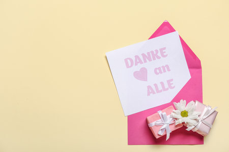 Card with text DANK AN ALLE, daisy flower and gift boxes on beige backgroundの写真素材