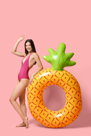 Happy young woman with inflatable ring on pink backgroundの写真素材