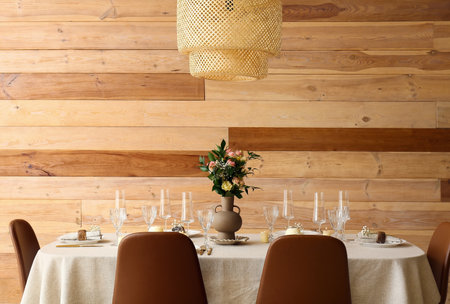 Stylish table setting with beautiful flowers near wooden wall