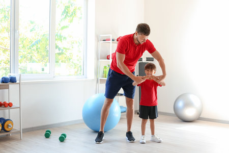 Male coach training with little boy in gymの写真素材