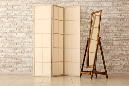 Beige folding screen and mirror near light brick wallの写真素材