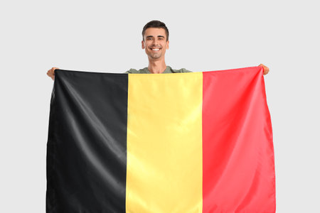 Young man with flag of Belgium on light backgroundの写真素材