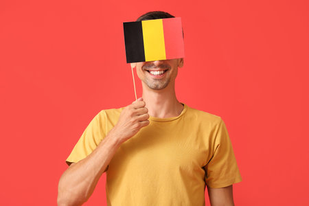 Young man with flag of Belgium on color backgroundの写真素材