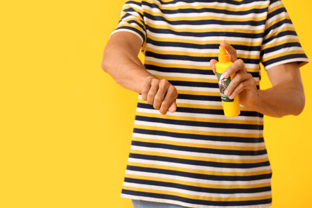 Young man with mosquito repellent on color backgroundの写真素材