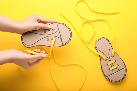 Woman with shoe lacing cards on color background, closeup