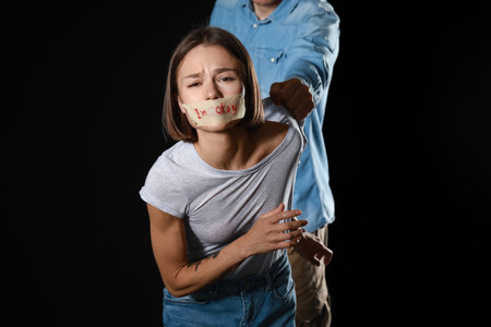 Man beating scared woman on dark background. Violence conceptの写真素材