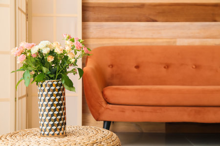Vase with beautiful roses on rattan pouf in roomの写真素材