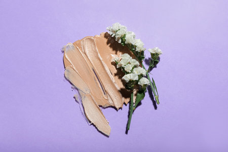 Smears of makeup foundation and flowers on purple backgroundの写真素材