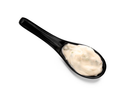 Caesar salad dressing in black spoon on white backgroundの写真素材