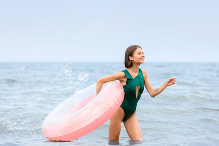 Beautiful young woman with inflatable ring at sea resort