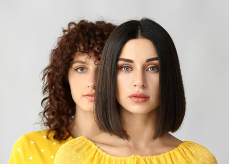 Portrait of beautiful sisters on gray background