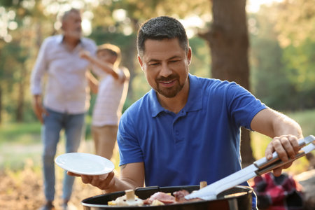 Handsome man cooking food on grill at barbecue partyの写真素材