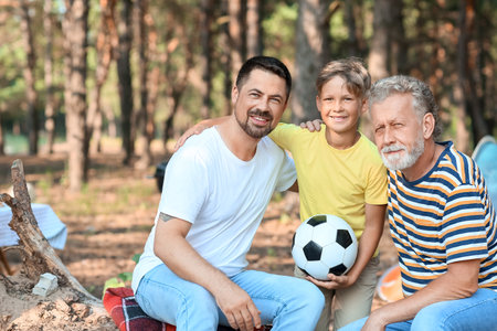 Little boy with ball, his father and grandfather in the forestの写真素材