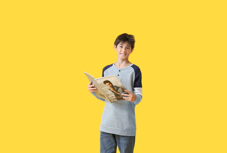 Teenage boy with magazine on yellow background