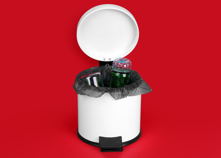 Open rubbish bin with trash on red backgroundの写真素材