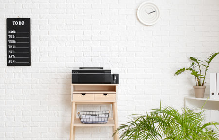 Interior of room with standing desk and board with to do list on white brick wall
